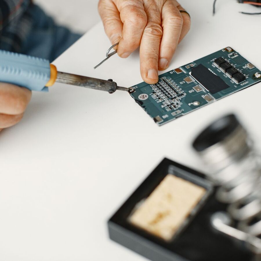 Technician soldering a component onto an electronic board